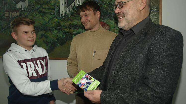 3. Bürgermeister Franz Kuhn und PHM Stefan Löhser überreichen das Lotsenbuch an Kevin Seufert. Foto: Stefan Geiger