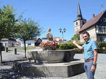 Bürgermeister Jörg Neubauer steht vor dem Wahrzeichen des Bierdorfes, der "Jungferkättl", einem Dorfbrunnen, der auch zur Kerwa Bier ausgießt. Im Hintergrund schaut er auf Großprojekte wie das evangelische Gemeindezentrum mit Sanierung des Lerners-Hauses und auf eine Grünfläche der ehemaligen Brauhaus-Brache, die einer Nutzung zugeführt werden wird.  Foto: K.- H. Hofmann