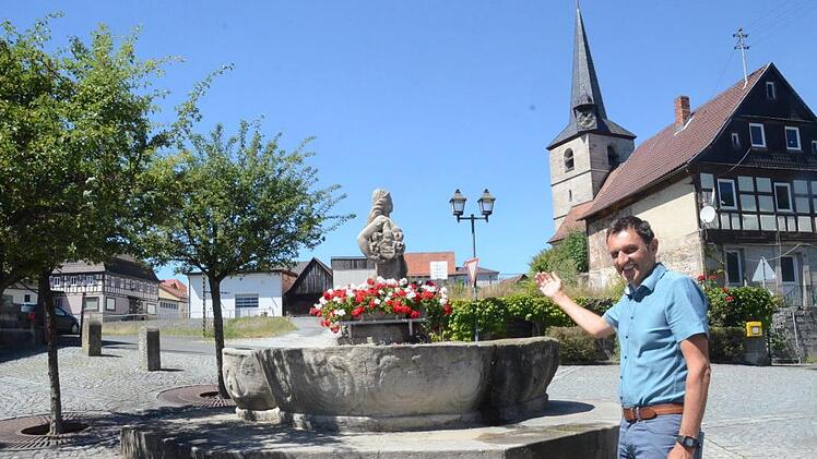 Bürgermeister Jörg Neubauer steht vor dem Wahrzeichen des Bierdorfes, der "Jungferkättl", einem Dorfbrunnen, der auch zur Kerwa Bier ausgießt. Im Hintergrund schaut er auf Großprojekte wie das evangelische Gemeindezentrum mit Sanierung des Lerners-Hauses und auf eine Grünfläche der ehemaligen Brauhaus-Brache, die einer Nutzung zugeführt werden wird.  Foto: K.- H. Hofmann