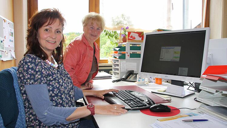 Karin Seufert (links) lässt sich von ihrer Multiplen Sklerose nicht unterkriegen: Dank ihres Arbeitgebers und der Rentenversicherung kann sie ihrer Arbeit im Sekretariat der Bad Kissinger Berufsschule nachgehen. Im Hintergrund Gerda Peters von der Selbsthilfegruppe. Foto: Ralf Ruppert
