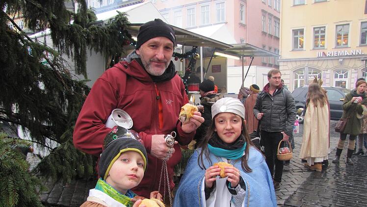 Die Sternsinger Erik und Luisa lassen sich zusammen mit ihrem Vater  Andreas Lurz jeweils eine Bratwurst als Stärkung schmecken. Vater Andreas gehört zu den  90000 ehrenamtlichen Helfern der Sternsingeraktion.  Foto: Martin Koch