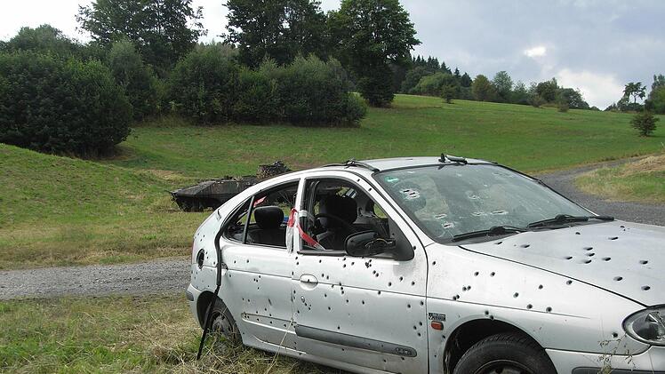 Zerschossener Pkw, im Hintergrund ein abgewracktes gepanzertes Fahrzeug. Foto: Joachim Rübel