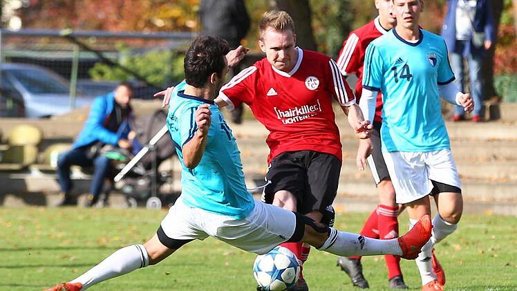 Der Lichtenfelser Daniel Oppel (in Rot) brachte seine Mannschaft mit dem 1:0 auf die Siegerstraße. Die beiden Anschlusstreffer des Forchheimers Andi Mönius (hier grätschend) reichten nicht. Die Jahn-Abwehr um Innenverteidiger Sandro Gumbrecht (re.) machte gegen den Aufsteiger keine gute Figur.  Foto: Sportfoto Zink