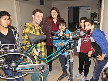Claudia Fischer-Curdts (Mitte) von der Firma FTE lässt sich von der Heiterkeit der Buben in der Fahrradwerkstatt anstecken. Zusammen mit Thomas Herrmann (2. von links) und seinem "Lehrling" Mohammad Abukasch (3. von rechts) sowie anderen Werkstattbesuchern ist sie froh, dass Fahrräder verkehrssicher hergerichtet werden können. Foto: Helmut Will