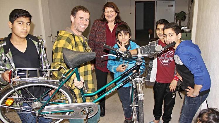 Claudia Fischer-Curdts (Mitte) von der Firma FTE lässt sich von der Heiterkeit der Buben in der Fahrradwerkstatt anstecken. Zusammen mit Thomas Herrmann (2. von links) und seinem "Lehrling" Mohammad Abukasch (3. von rechts) sowie anderen Werkstattbesuchern ist sie froh, dass Fahrräder verkehrssicher hergerichtet werden können. Foto: Helmut Will