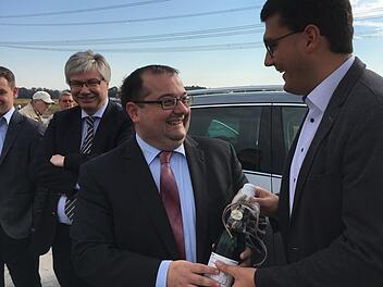 Jonas Merzbacher (r.) gratuliert seinem Amtskollegen Thomas Söder   bei der Kreisstraßenfreigabe mit einem Präsent gleich auch zum Geburtstag, das verfolgen die Gemeindeoberhäupter und Kreistagskollegen Rüdiger Gerst und Johannes Maciejonczyk (l.) .Foto: Anette Schreiber