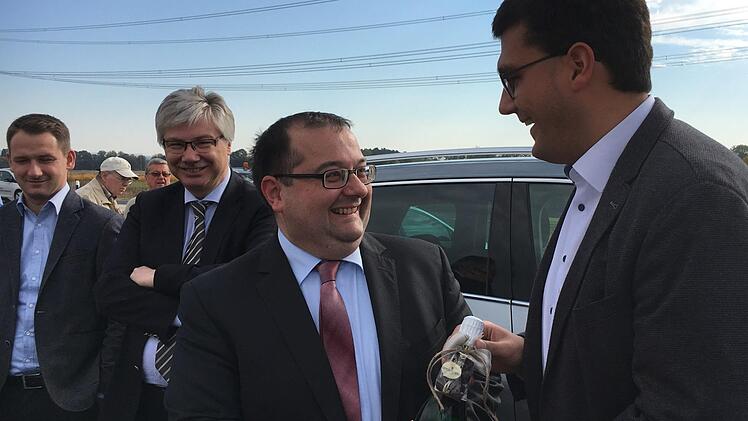 Jonas Merzbacher (r.) gratuliert seinem Amtskollegen Thomas Söder   bei der Kreisstraßenfreigabe mit einem Präsent gleich auch zum Geburtstag, das verfolgen die Gemeindeoberhäupter und Kreistagskollegen Rüdiger Gerst und Johannes Maciejonczyk (l.) .Foto: Anette Schreiber