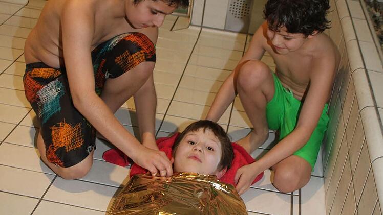 Rührend kümmern sich Eddie Zimbelmann (12) und Ömel Portakal (10) um den Verletzten Niklas Knörrer (7). "Ich hab einen Schock", erklärt Niklas selbstbewusst. Foto: Sonja Adam