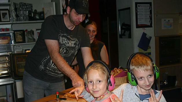 Die j&uuml;ngsten Besucher waren Ronja (8) und David (10), die auf Anraten ihrer Eltern ihre Ohrensch&uuml;tzer dabei hatten. Hinter ihnen sind Sabine Moros und Achim Schwinn aus dem Vorstand der Musikinitiative Ha&szlig;berge zu sehen, wie sie sich um die Verpflegung an diesem Abend k&uuml;mmern.Monika Schraut