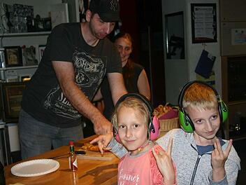Die jüngsten Besucher waren Ronja (8) und David (10), die auf Anraten ihrer Eltern ihre Ohrenschützer dabei hatten. Hinter ihnen sind Sabine Moros und Achim Schwinn aus dem Vorstand der Musikinitiative Haßberge zu sehen, wie sie sich um die Verpflegung an diesem Abend kümmern.Monika Schraut