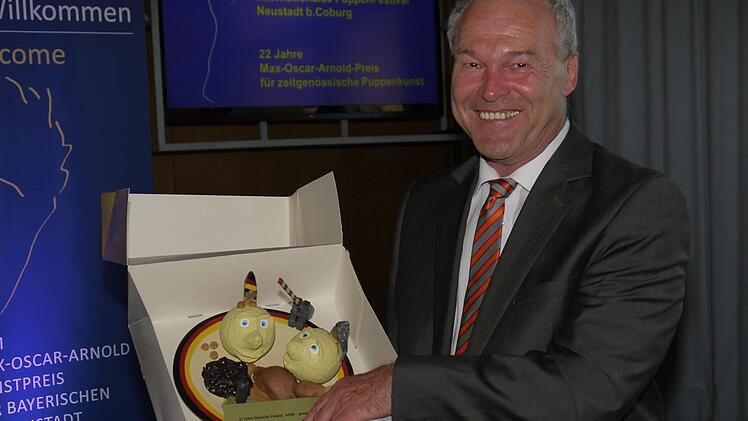 Symbolische Kunst: Frank Rebhan zeigt die Geburtstagstorte, die der Puppenkünstler Christoph Jakobs der Stadt Neustadt zum Jubiläum "25 Jahre Puppenfestival" hat anfertigen lassen. Foto: Berthold Köhler