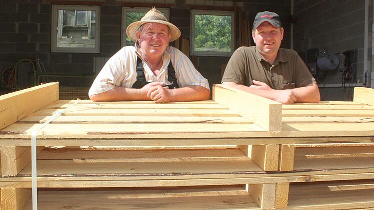 Johann (links) und Stefan Ellner mit einem Stapel Paletten, die sie in ihrem Sägewerk in Weisbrem hergestellt haben. Foto: Matthias Einwag