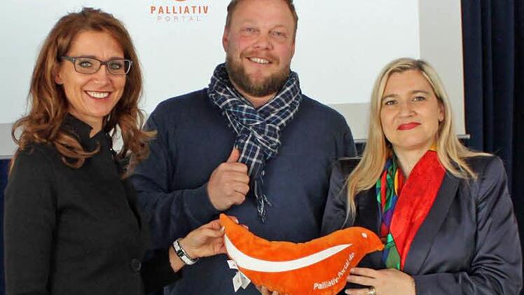 Jörg Cuno bei der Übergabe des Taubenkissens an Melanie Huml. Stephanie Denzler (l) will als Botschafterin für "Columba" werben.