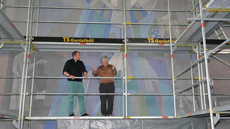 Pfarrer Michael Kubatko (links) und Kirchenpfleger Siegbert Holzheimer (rechts) auf dem Gerüst hinter dem Altar. Unter anderem das Wandbild soll hier neu gefasst werden.  Foto: Björn Hein