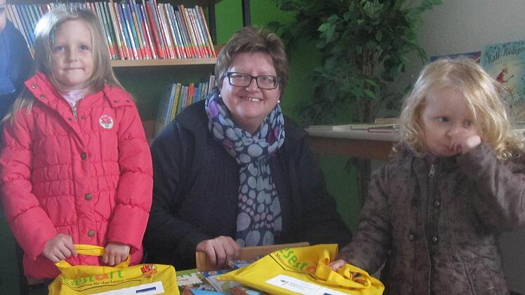 Ihre "Lesestart-Sets" holen sich Helena und Rosalie aus Singenrain zusammen mit ihrer Oma bei Petra Knüttel vom Bücherei-Team in der Bücherei im Pfarrheim ab. Foto: Oswald Türbl