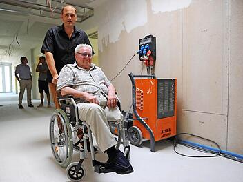 Michael Wehner und sein 94-jähriger Großvater Johann Quadflieg inspizieren die neuen Räume des künftigen Pflegeheims in Burkardroth. Neben den beiden steht ein Bautrockner, der eingesetzt wird, um den Estrich zu trocknen. Foto: Kathrin Kupka-Hahn
