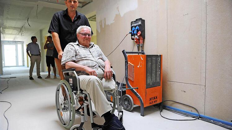 Michael Wehner und sein 94-jähriger Großvater Johann Quadflieg inspizieren die neuen Räume des künftigen Pflegeheims in Burkardroth. Neben den beiden steht ein Bautrockner, der eingesetzt wird, um den Estrich zu trocknen. Foto: Kathrin Kupka-Hahn