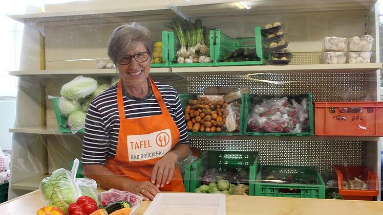 Eine Mitarbeiterin der Tafel präsentiert  die Lebensmittel hinter der Schutzscheibe. Foto: Julia Raab