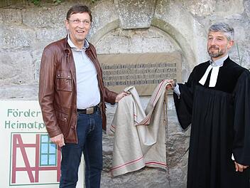 Der Vorsitzende des Fördervereins für Heimatpflege in Grub am Forst gab zusammen mit Pfarrer Thomas Amberg die Tafel an der Kirchenmauer der St.-Ägidius-Kirche frei. Foto: Michael Stelzner