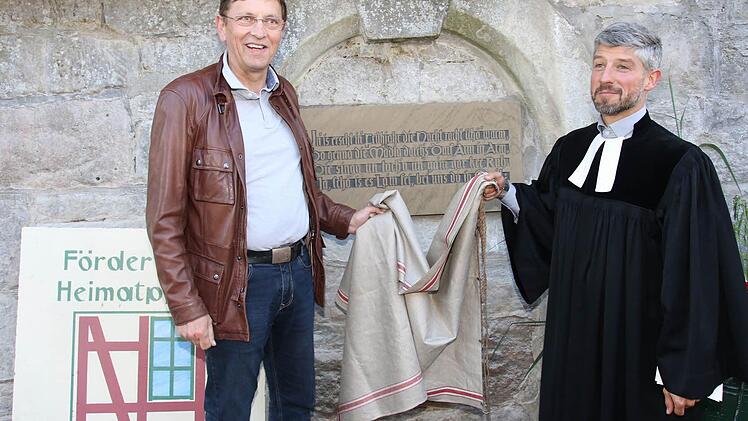 Der Vorsitzende des Fördervereins für Heimatpflege in Grub am Forst gab zusammen mit Pfarrer Thomas Amberg die Tafel an der Kirchenmauer der St.-Ägidius-Kirche frei. Foto: Michael Stelzner