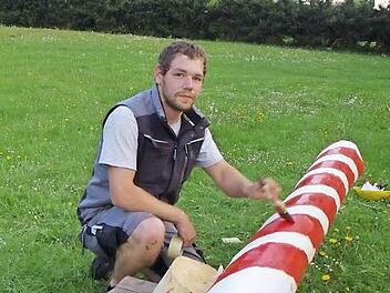 Simon Kraus verziert den Maibaum mit dem typischen rot-weißen Farbmuster. Fotos: Heike Schülein