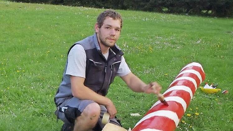 Simon Kraus verziert den Maibaum mit dem typischen rot-weißen Farbmuster. Fotos: Heike Schülein