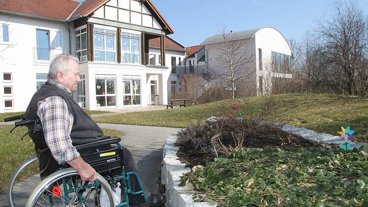 Das neue Wahrzeichen des BRK-Seniorenheims Marktleugast: der auf die Südseite verlagerte neue Haupteingang (hinten, rechts) mit der markanten Dachform. Neu angelegt ist auch der Garten mit rollstuhlgerechten Wegen, der beim Heimbeiratsvorsitzenden Robert Schott und bei seinen Mitbewohnern sehr gut ankommt. Foto: Archiv/Stephan Tiroch