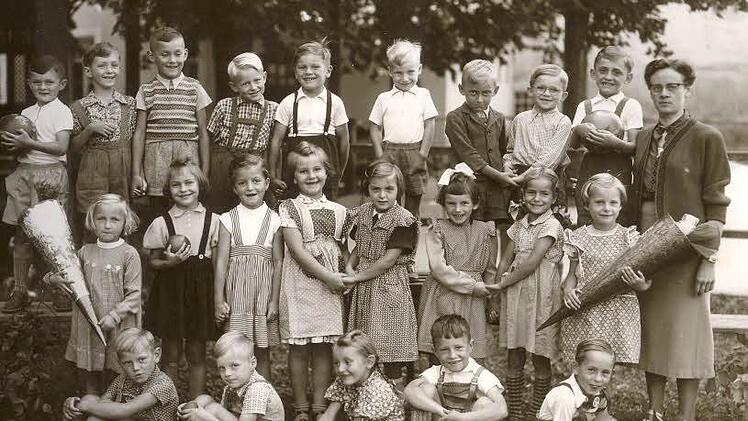 Bild von der Einschulung. Obere Reihe (von links): Davis Schott, Wilfried Zirbs, Bernd Kolb, Werner Reimann, Herbert Schmidt, Helmut Moncken, Gerhard Ludwig, Peter Fuchs, Anton Spitzenpfeil, Lehrerin Frau Dörfler.Mittlere Reihe (von links): Rita Weigel, Maria Kraus, Christa Dresel, Siegrid Weidner, Ottilie Gerber, Gertraud Dresel, Ursula Dittebrand, Karola Kremer. Untere Reihe (von links): Günther Vießmann, Reinhard Schuster, Irmgard Jahreis, Werner Gebelein und Horst Rott.