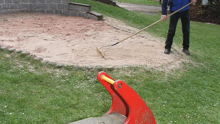 Tom Schütz rechnet den Sand glatt, damit der Spielplatz auch optisch eine Augenweide ist.