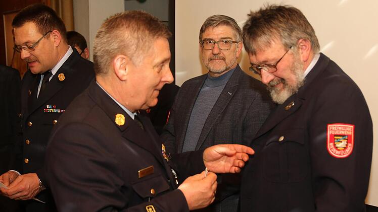 Kreisbrandrat Manfred Lorenz heftet bei der Hauptversammlung Heinz Großmann das Feuerwehrehrenzeichen für 40 Jahre Feuerwehrdienst an. Landrat Michael Busch (dahinter) würdigte die Verdienste des Jubilars.  Foto: Michael Stelzner