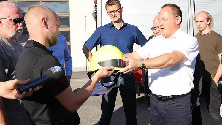 Stefan Büttner, in diesem Moment schon Ex-Kommandant der Feuerwehr Lützelbuch, überreicht symbolisch für alle Ausrüstungsgegenstände einen Helm an Stadtbrandinspektor Daniel Fritz.