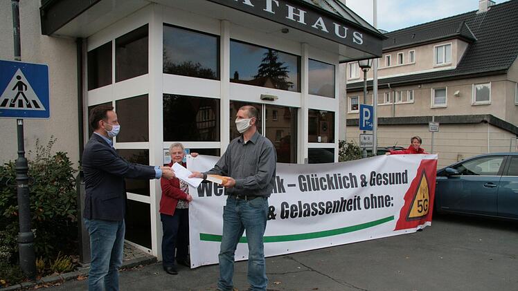 Alexander Kaiser (vorne rechts) von der Initiative "Weniger Funk - glücklich und gesund" überreichte eine Liste mit Unterschriften von Gegnern des geplanten Mobilfunkmasts  aus Motschenbach und Wüstenbuchau an Bürgermeister Robert Bosch (links). Foto: Jürgen Gärtner