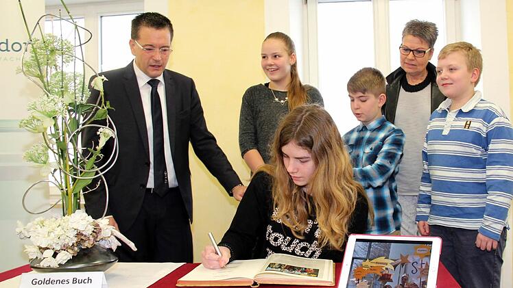 Bürgermeister Karten Fischkal (links ) und seine Stellvertreterin Jutta Köhler (5. v. l.) sind dabei, als sich nicht nur Tina Noppenberger (sitzend), sondern auch Anna-Lena Dittrich (2. v. l.), Fabian Lamm (4. v. l.) und Julius Petersilka (6. v. l.) ins Goldene Buch eintragen.