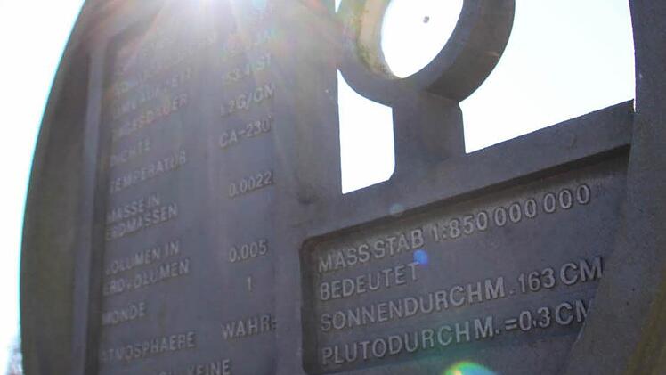 Die halb verdunkelte Sonne blitzt am Freitagvormittag durch die Skulptur des Pluto am Planetenweg in Unnersdorf.