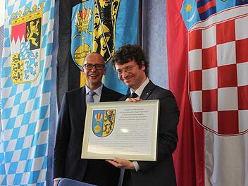 Predrag Šustar, der kroatische Minister für Wissenschaft, Bildung und Sport, freute sich über ein Erinnerungsgeschenk von Landrat Christian Meißner, auf dem das Landkreiswappen erläutert wird. Foto: Popp
