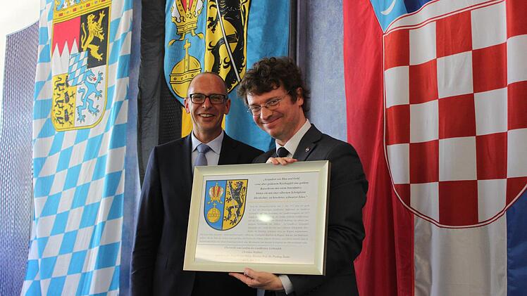 Predrag Šustar, der kroatische Minister für Wissenschaft, Bildung und Sport, freute sich über ein Erinnerungsgeschenk von Landrat Christian Meißner, auf dem das Landkreiswappen erläutert wird. Foto: Popp