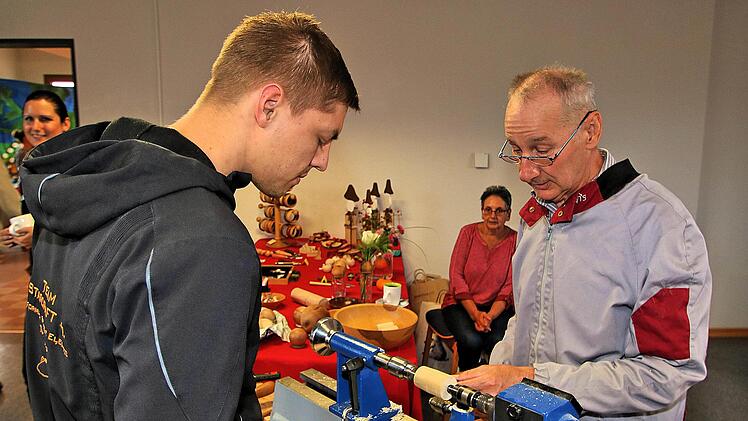 Drechsler Werner Schneider aus Münnerstadt (rechts) führte seine Kunst vor.  Auch junge Leute zeigten sich interessiert. Foto: Dieter Britz
