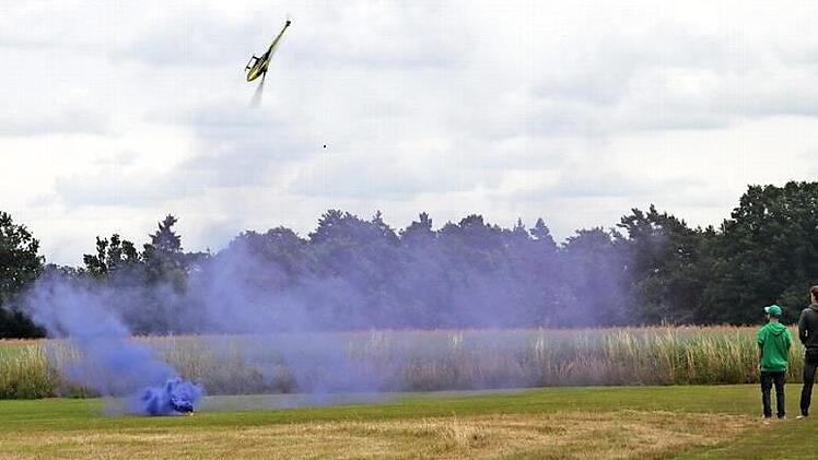 Flink lässt Erik Fischer aus Rothwind den Modellhubschrauber um die lila Rauchwolke tänzeln, die vom Boden aufsteigt. Die Idee dazu hatte Daniel Götz aus Kulmbach. Foto: Stephan Stöckel
