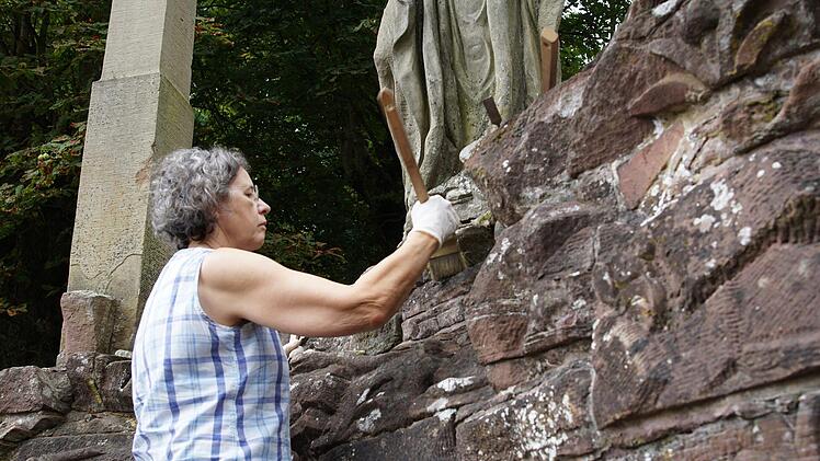 Birgid Muth reinigt die Wand von Moosen und Bewuchs.Foto: Arkadius Guzy