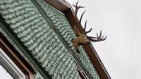 Vom Giebel blickt ein Hirschkopf hinab.