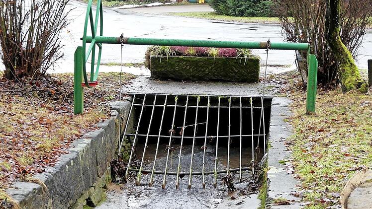 Bei starken Regenfällen schießt das Wasser des Feulner Baches über das Gitter hinweg auf die Dorfstraße.