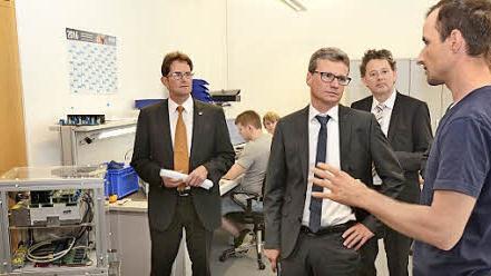 Beeindruckende Forschungsarbeiten. TTZ-Mitarbeiter Julian Endres (rechts) zeigt Staatssekret&auml;r Bernd Sibler einen Stromrichter im Beisein des stellvertretenden Landrats Peter Suckf&uuml;ll (links) und TTZ-Leiter Professor Ansgar Ackva.  Foto: Stefan Kritzer