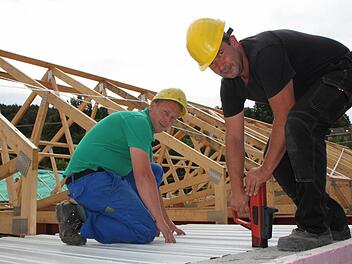 Das Flachdach wird schon gesetzt: Sandro Hoppe (links) und Harald Eitner befestigen Trapezbleche. Fotos: Ulrike Müller