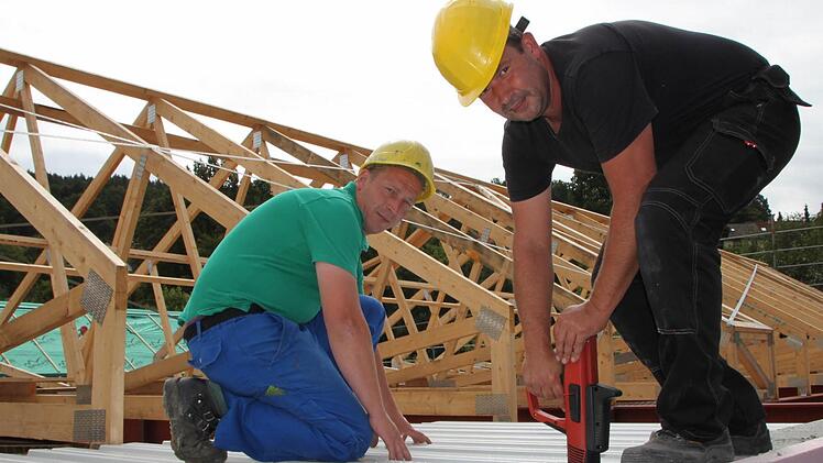 Das Flachdach wird schon gesetzt: Sandro Hoppe (links) und Harald Eitner befestigen Trapezbleche. Fotos: Ulrike Müller
