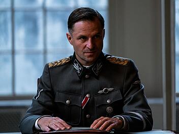 Ein L&auml;cheln zur Planung von millionenfachem Massenmord: Reinhard Heydrich (Philipp Hochmair), Chef des Reichssicherheitshauptamts, der Sicherheitspolizei und des SD, sitzt der Wannseekonferenz am 20. Januar 1942 vor.