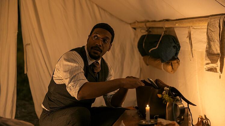 Dr. George Tann (Jocko Sims) ist Arzt in Kansas, in der N&auml;he des Ortes, wo sich Familie Ingalls niederl&auml;sst. Tann war eine reale Person und behandelte die Ingalls' auch in den B&uuml;chern. Er hatte w&auml;hrend des B&uuml;rgerkriegs in der Unionsarmee gedient und war danach, wie viele Afroamerikaner, nach Kansas gezogen.