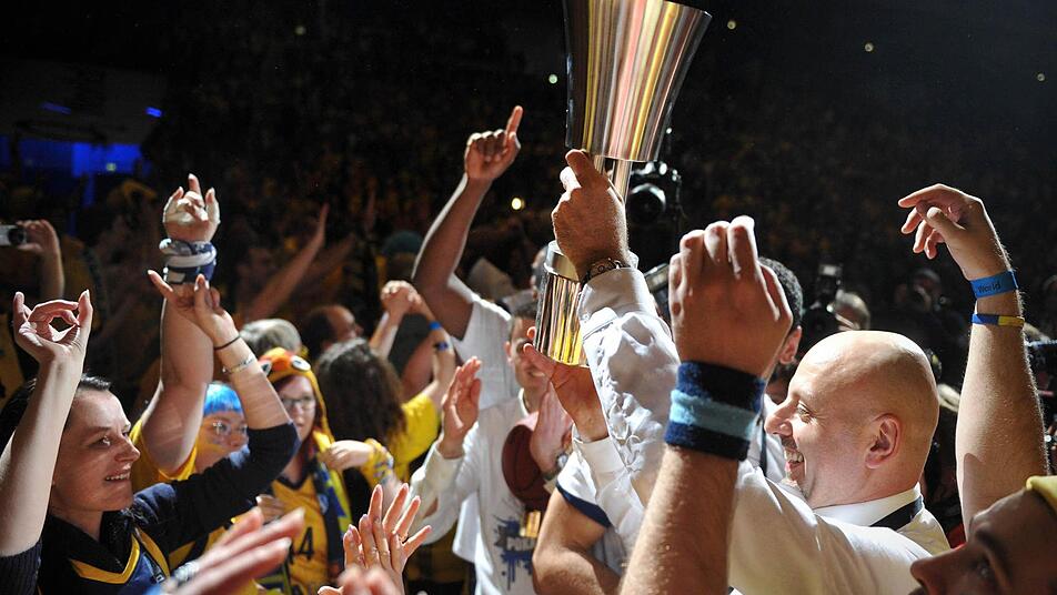 Berlins Trainer Sasa Obradovic (r) hält den Pokal hoch vor dem Berliner Fanblock. Foto: Jan-Philipp Strobel/dpa
