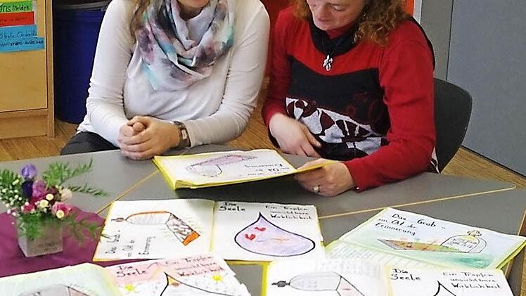 Wann, wie und warum ist man tot? Mit diesen schwierigen Fragen haben sich die Grundschüler künstlerisch auseinandergesetzt. Hospizkoordinatorin Annette Hümmer (links) und Lehrerin Yvonne Fritz-Schilling betrachten die Zeichnungen der Zweitklässler.  Foto: Heike Schülein