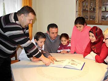 So sahen Küps und seine Ortsteile früher aus. Uwe Böhm (links) und seine Frau Silke (rechts) zeigen der Familie Alhay Mawas einen Bildband mit alten Ansichten. Asad, Mohammed, Sama, Tasmin und Diana (von links) interessieren sich für alles in ihrer neuen Heimat. Foto: Friedwald Schedel
