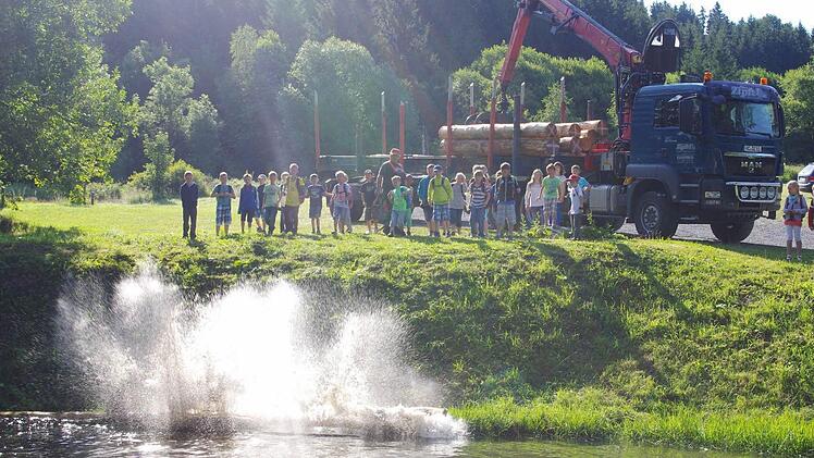 Josef Pfadenhauer und die Kinder beförderten die Baumstämme ins Wasser. Foto: Heike Schülein